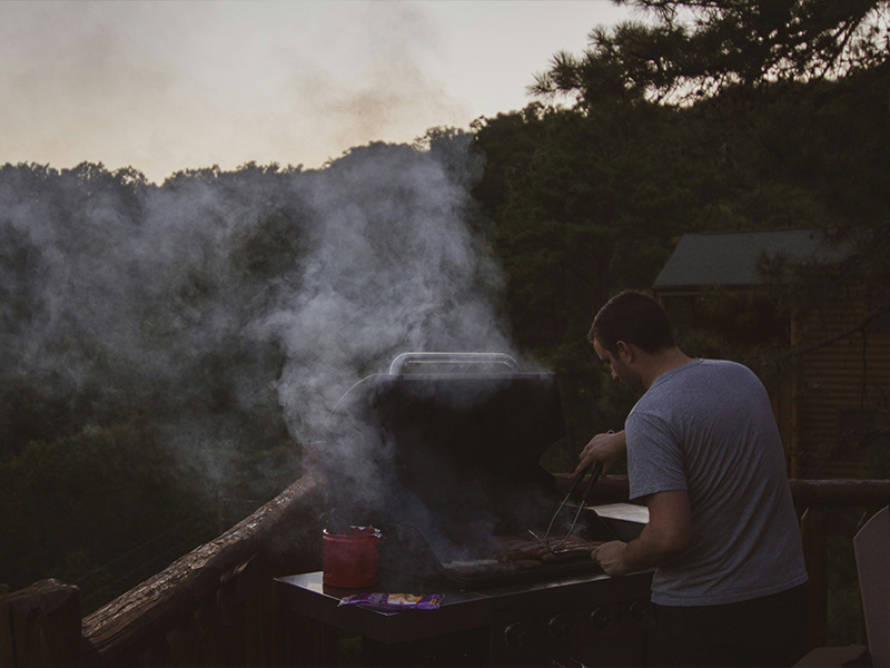 L-TOOLS outdoor grill with smoke rising, capturing the authentic BBQ experience.