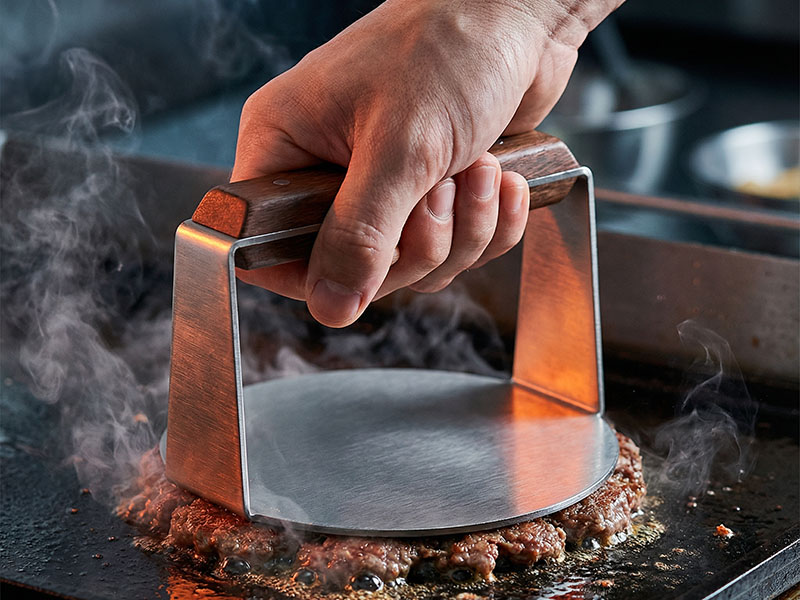 L-TOOLS hand using a burger press to shape patties, showcasing BBQ prep tools in action.