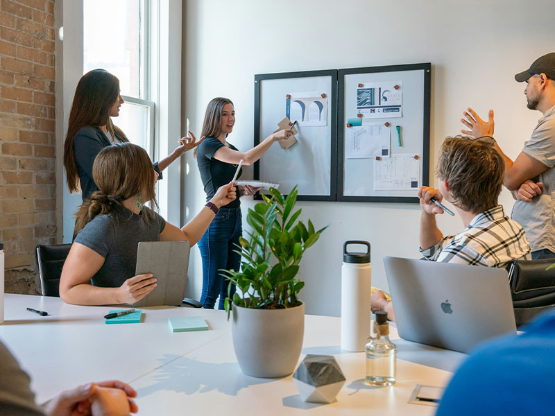 L-TOOLS office meeting with team presenting ideas on a whiteboard, highlighting professional strategy sessions.