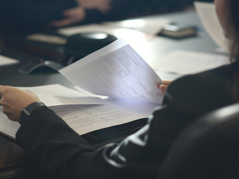 L-TOOLS person reviewing documents with focused lighting, representing business analysis and decision-making.