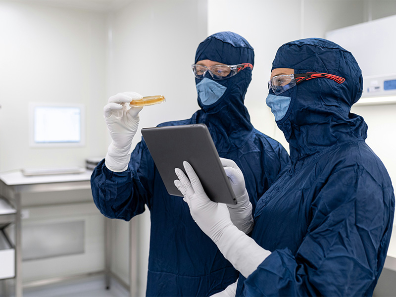 L-TOOLS technician using tablet to monitor automated production machinery in a high-tech factory.