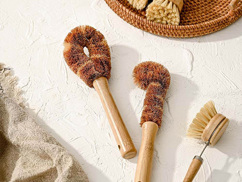 L-TOOLS hand rinsing a natural fiber brush in a glass, highlighting water-efficient cleaning.