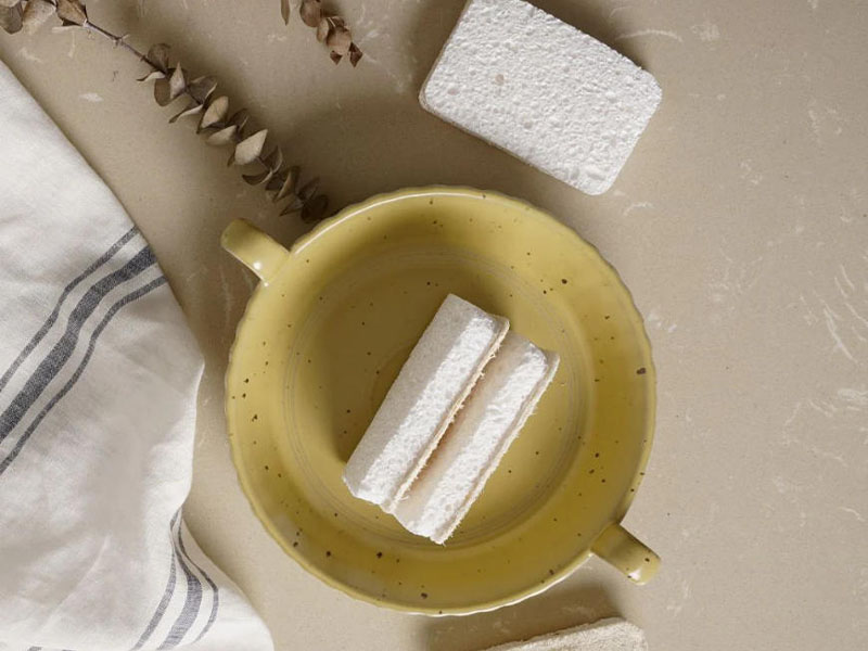 L-TOOLS wooden cleaning brushes soaking in a bowl, showcasing natural material kitchen tools.