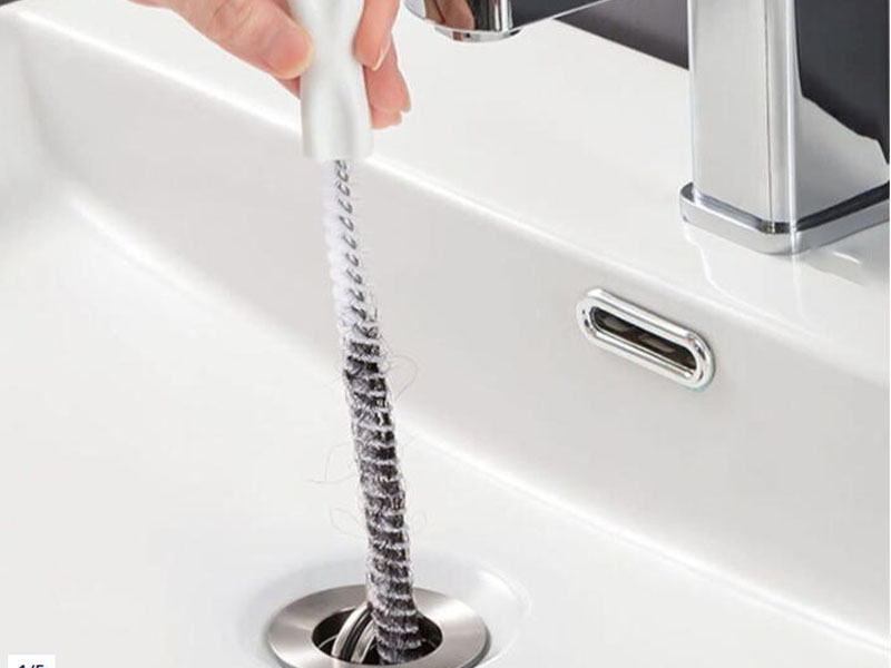 L-TOOLS close-up of stainless steel sink brush being used to clean drain effectively.