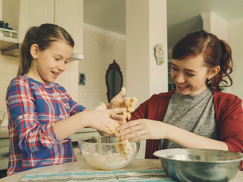 L-TOOLS children and adults using cookie cutters to shape dough, emphasizing family-friendly baking activity.