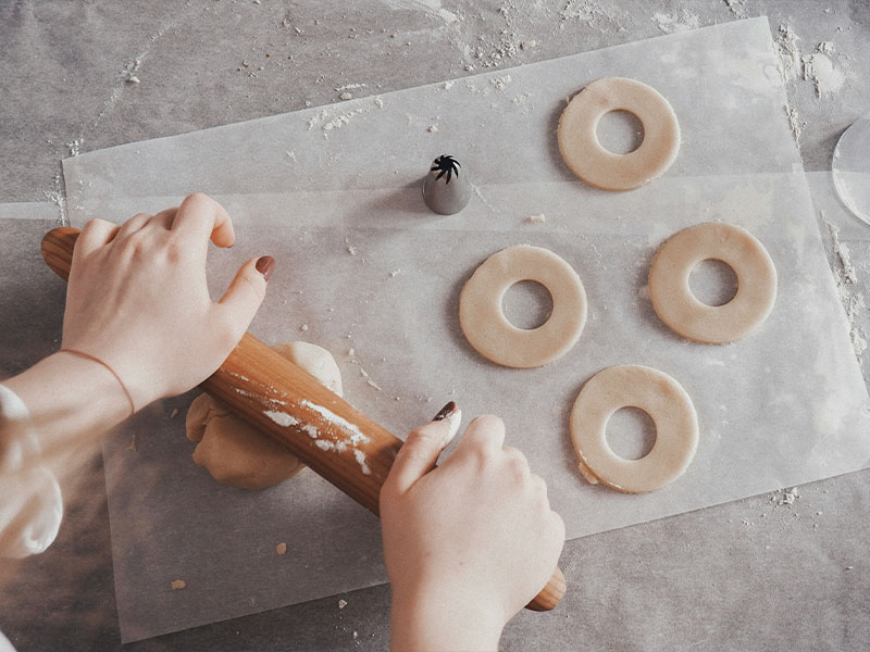 L-TOOLS person cutting cookie shapes from dough, highlighting festive or creative baking.