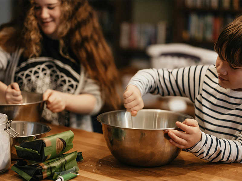 L-TOOLS girl using a whisk to stir ingredients, emphasizing fun and learning in baking.