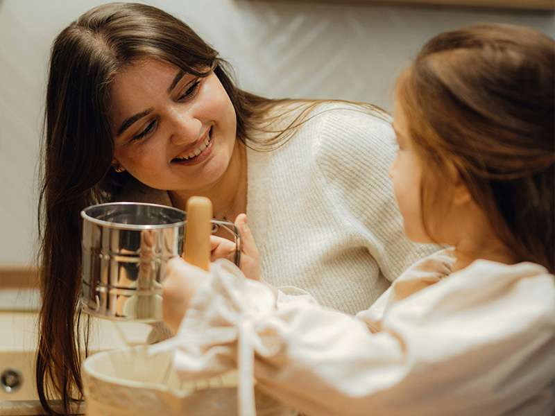 L-TOOLS mother and daughter drinking water and chatting in a kitchen, showcasing joyful home moments.