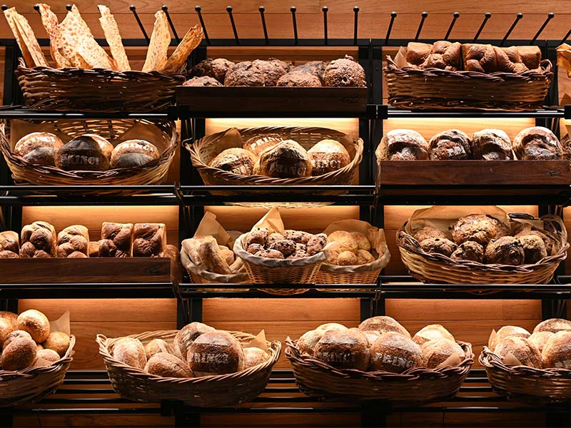 L-TOOLS freshly baked bread displayed on wooden shelves, emphasizing artisanal baking and food presentation.