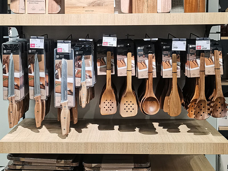 L-TOOLS retail display of wooden and stainless steel kitchen utensils, emphasizing organized product presentation.