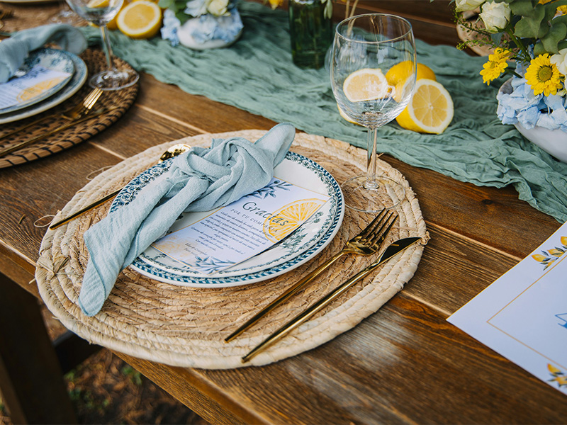 L-TOOLS individual table setting with woven placemat, napkin, and lemon garnish, highlighting attention to detail.