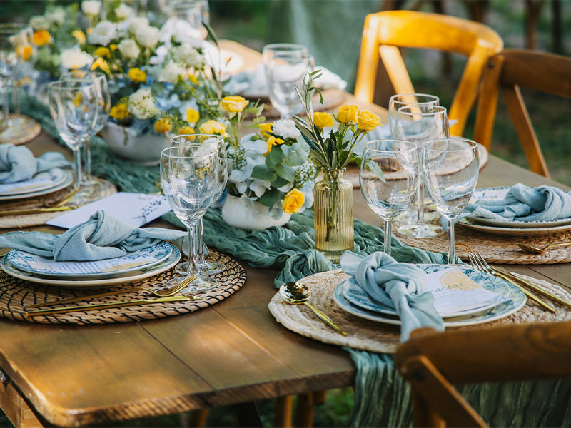 L-TOOLS outdoor dining table set with plates, napkins, and floral centerpieces, showcasing elegant table styling.